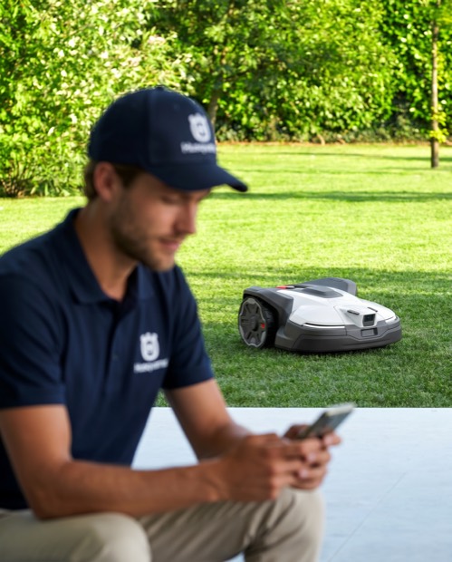 Worker setting up a robotic mower in a yard