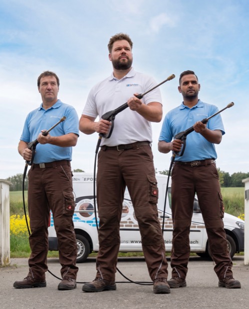 Three tradesmen with tools in front of their shop